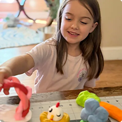 Child shaping colorful modeling dough at a table