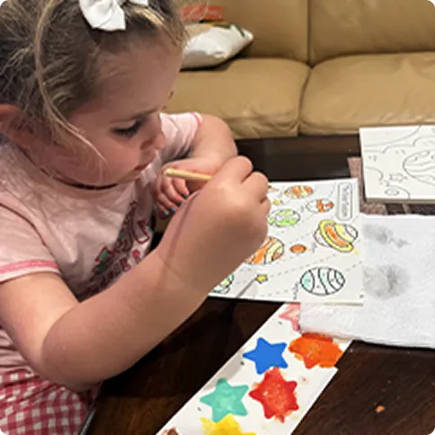Child coloring a dot-marker activity sheet at a table