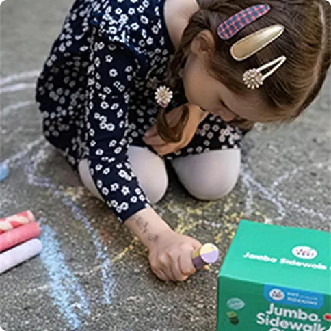 Child drawing with sidewalk chalk on the ground