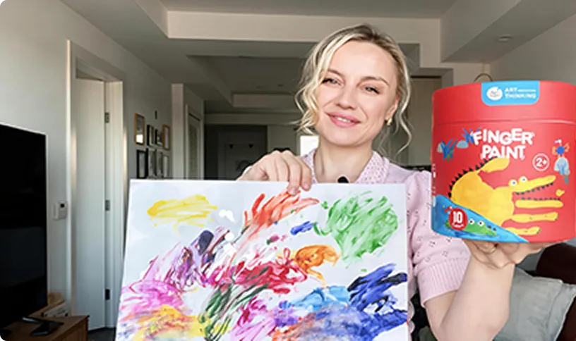 Parent showing a finger-painting artwork next to a paint cup