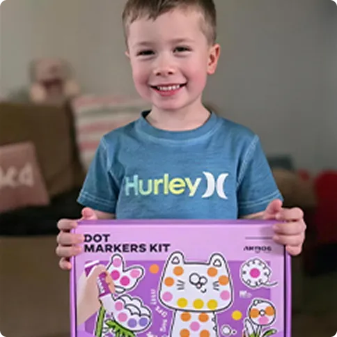 Child holding a dot markers kit box